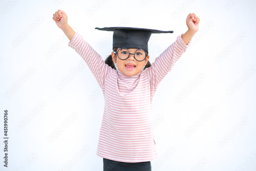 A little girl asia looks happy while celebrating his graduation and holding a diploma and graduation cap which increases the development and enhances outside the classroom learning skills concept. A little girl asia looks happy while celebrating his graduation and holding a diploma and graduation cap which increases the development and enhances outside the classroom learning skills concept.