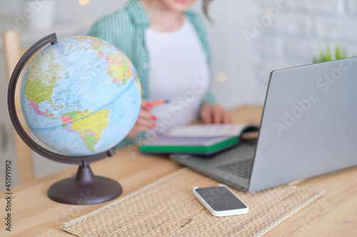 blurred globe in the foreground. in the background a woman works at a laptop, illustration of an international company or online profession. freelancer works remotely photo