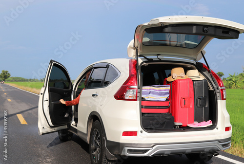 Closeup of rear side of white car carrying luggage, suitcases and other things with natural background. During lovely family holiday.