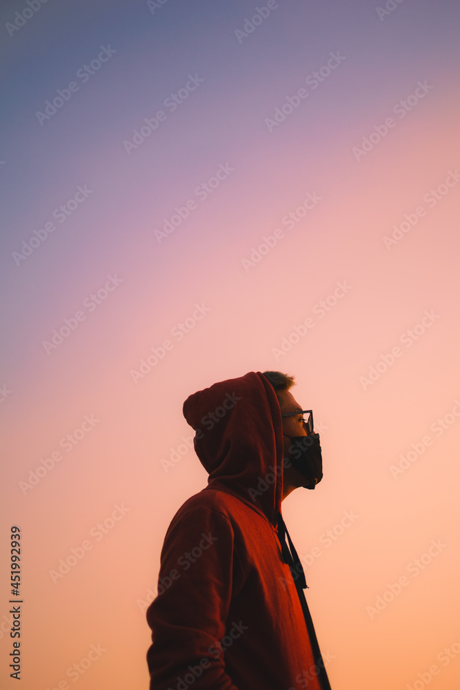 young man with mask in the middle of a beautiful sunset young man with mask in the middle of a beautiful sunset