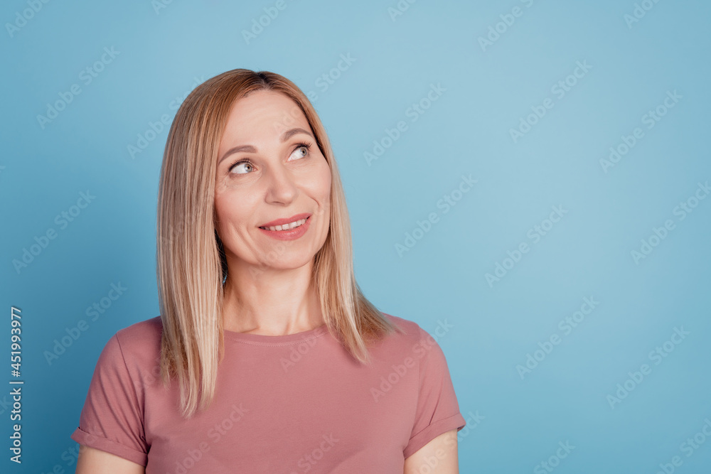 Photo of young attractive woman happy positive smile curious look empty space isolated over blue color background Photo of young attractive woman happy positive smile curious look empty space isolated over blue color background