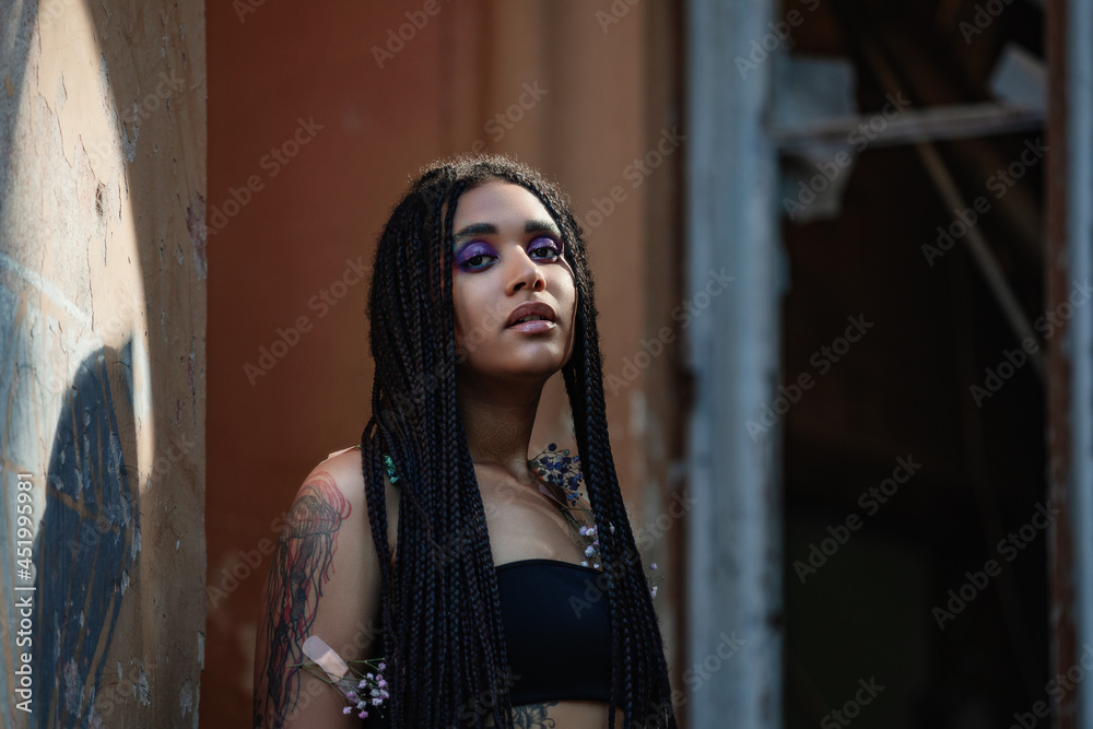 Obraz premium Portrait of a young beautiful tattooed girl with box braids hairstyle