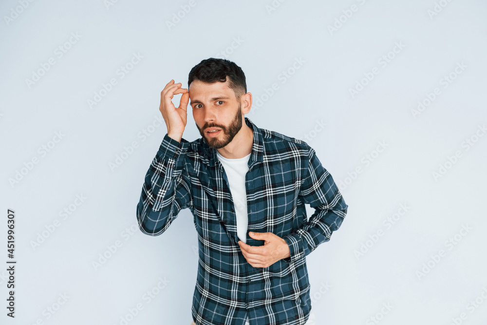 Looks into the camera. Young man in casual clothes standing indoors in the studio Looks into the camera. Young man in casual clothes standing indoors in the studio