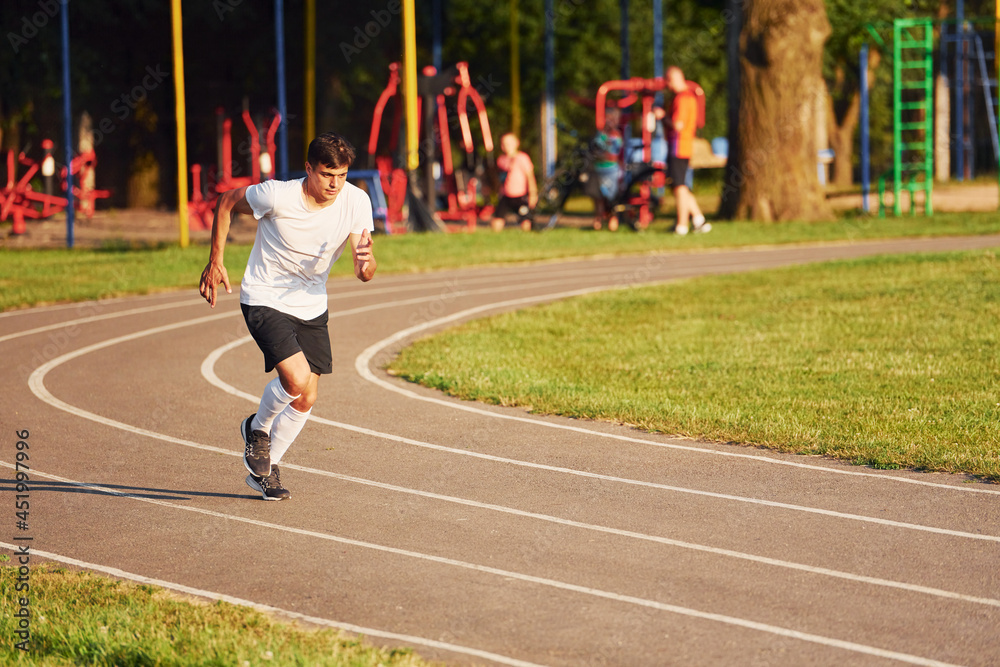 Man in sportive unifrom running on the track at daytime