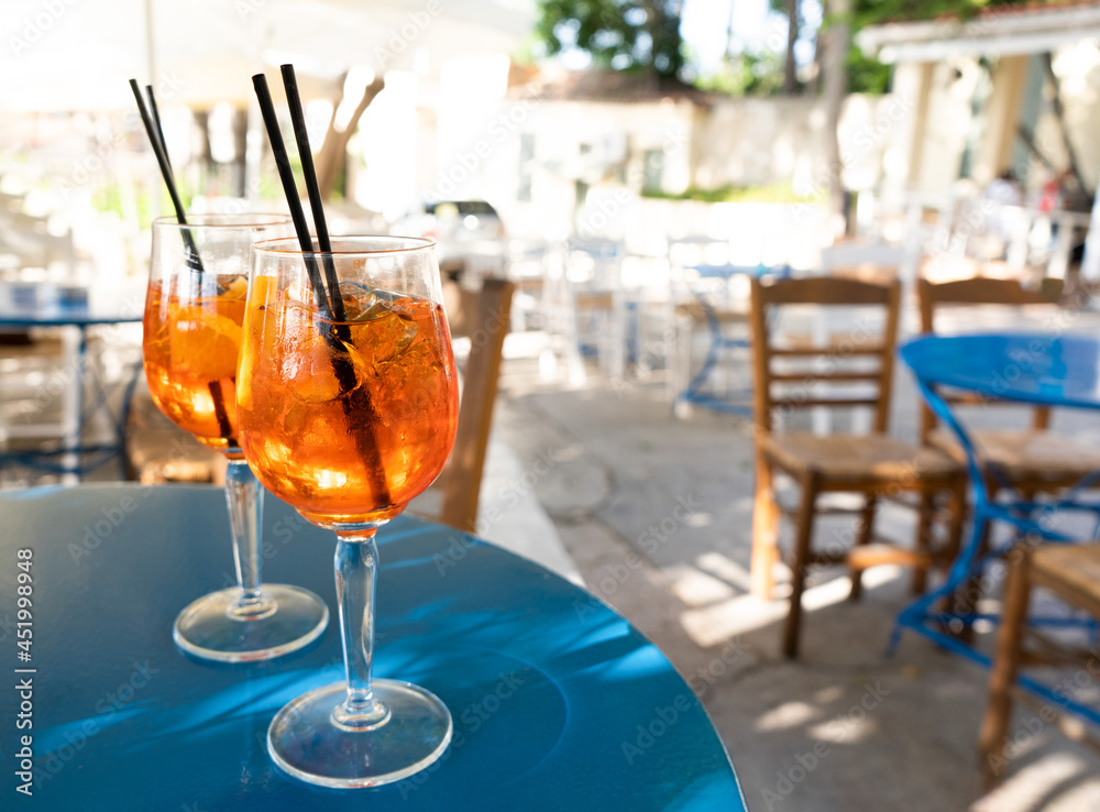 Two glasses with Aperol Spritz cocktail on a blue table in a Greek cafe in Athens Two glasses with Aperol Spritz cocktail on a blue table in a Greek cafe in Athens