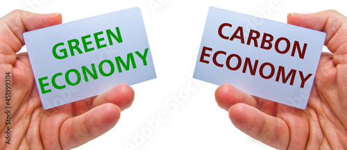 man hands holding cardstocks with the words green economy and carbon economy.