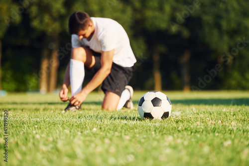 Ties laces. Young soccer player have training on the sportive field © standret