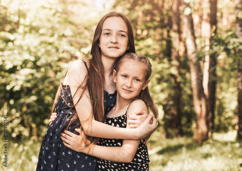 two girls sister hugging and smiling on the nature in the summer © Olya Komarova