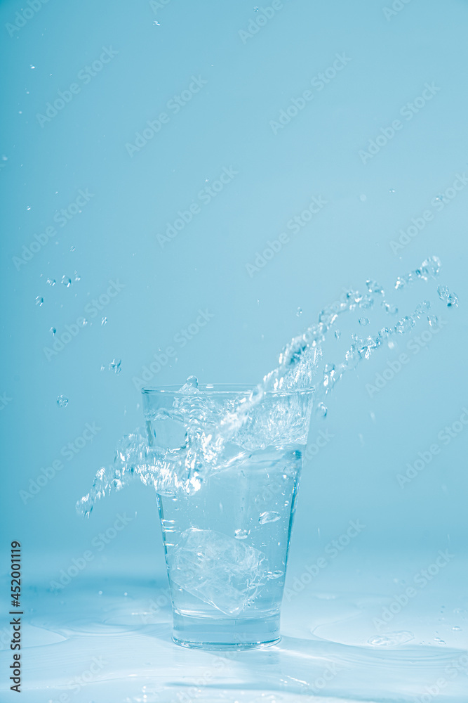 Ice cubes splashing into glass of water, isolated on white