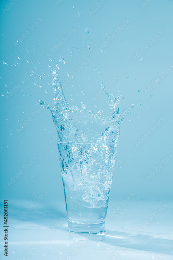 Ice cubes splashing into glass of water, isolated on white Ice cubes splashing into glass of water, isolated on white