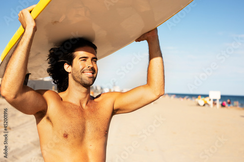 Handsome man with surfboard. Surfer taking a break on the beach..