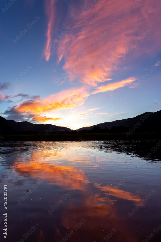 landscape silhouette The mountains, the sunset in the evening sky, and then the light hits the clouds is orange. There is a reflection in the river that feels relaxed There is space for text. landscape silhouette The mountains, the sunset in the evening sky, and then the light hits the clouds is orange. There is a reflection in the river that feels relaxed There is space for text.