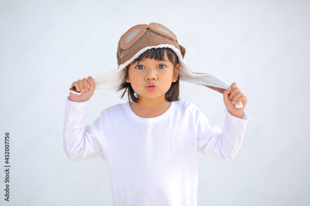 little girl dressed in a cap brown of a pilot. The child dreams of becoming a pilot which increases the development and enhances outside the classroom learning skills concept. on a white background. little girl dressed in a cap brown of a pilot. The child dreams of becoming a pilot which increases the development and enhances outside the classroom learning skills concept. on a white background.