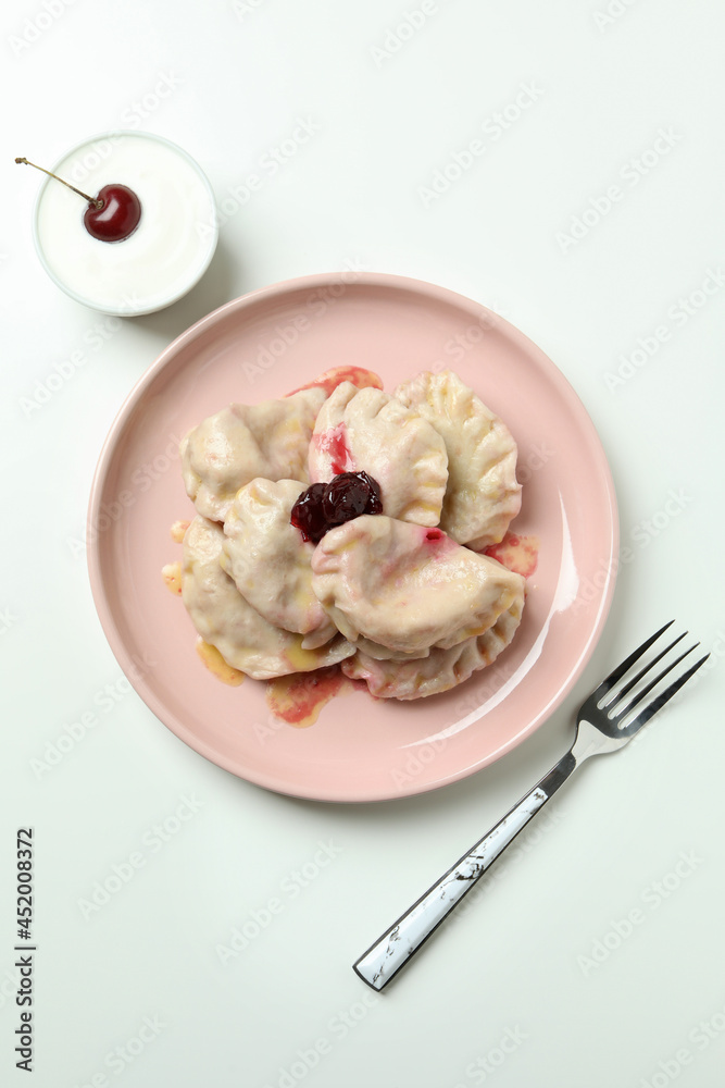 Plate with pierogi with cherry on white background