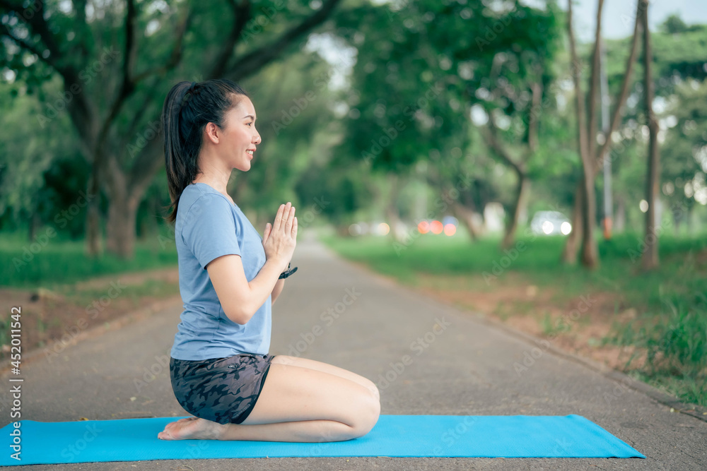 Asia woman practices yoga and meditates at park. Healthy lifestyle and Yoga concept.