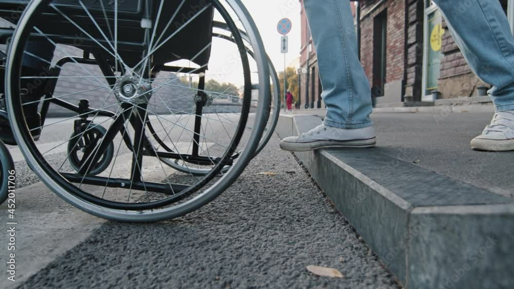 Closeup wheelchair wheel gently slowly descending from curb of