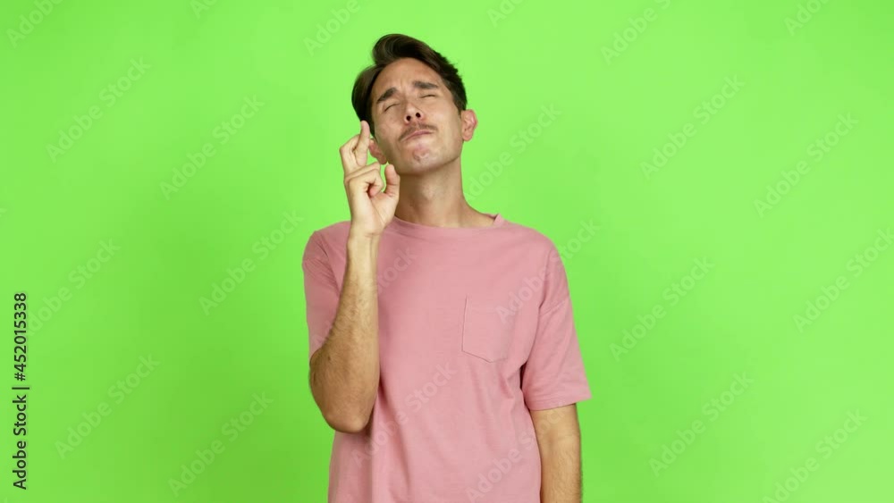 Young man with fingers crossing and wishing the best. Making a wish over isolated background. Green screen chroma key Young man with fingers crossing and wishing the best. Making a wish over isolated background. Green screen chroma key