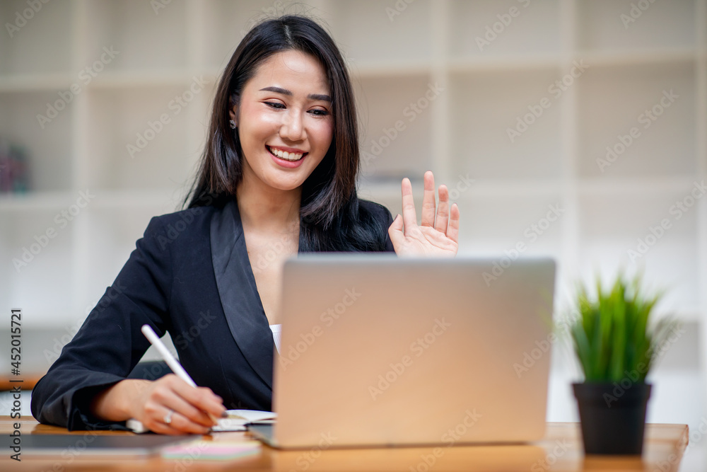 Confident business woman looking and speaking through the webcam while making a video conference with laptop from the office. Confident business woman looking and speaking through the webcam while making a video conference with laptop from the office.