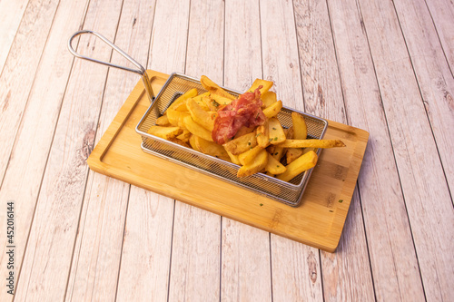 portion of homemade chips inside a metal container to fry in a deep fryer accompanied by fried ham