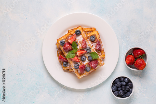 Belgian waffles with strawberries, blueberries and syrup, homemade healthy breakfast