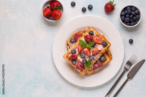 Belgian waffles with strawberries, blueberries and syrup, homemade healthy breakfast