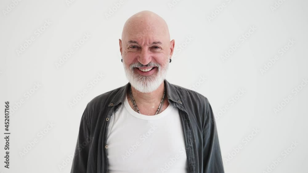 A smiling bald mature man posing to the camera standing isolated over white background in the studio A smiling bald mature man posing to the camera standing isolated over white background in the studio