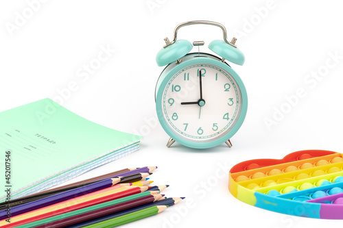 An alarm clock stands with notebooks and crayons - concept with space for text or other elements on the subject of school and time management in elementary school