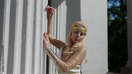 portrait of a blonde with big breasts and in a Greek chiton at the column. the camera is moving photo