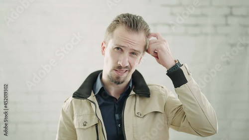 Portrait of male person unsure scratching head in slow motion 4K photo