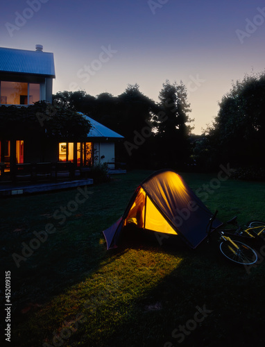 Evening shot of young boy inside tent pitched in backyard