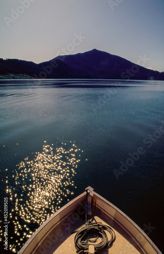 Bow of boat with rope and anchor on deck, moving through calm water