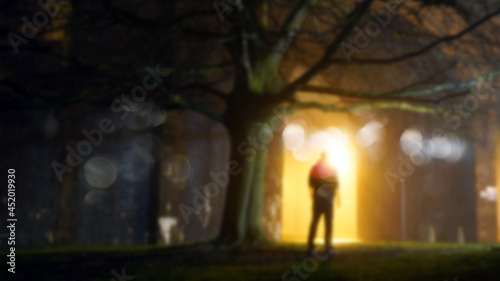A mysterious figure standing by street lights on a misty winters night. With a blurred, bokeh, out of focus edit