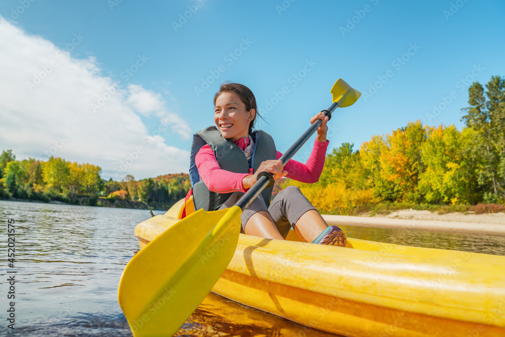 Naklejka premium Kayak fun water sports on river in Laurentians, Quebec, Canada. Summer travel destination. Happy Asian woman kayaker kayaking in lake.