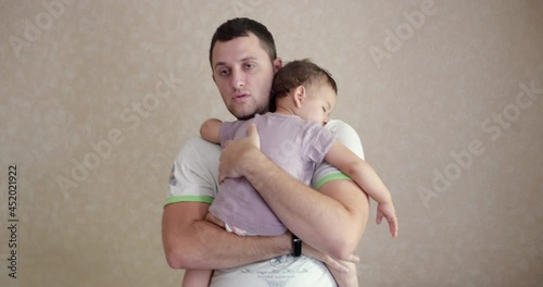 a small baby fell asleep in his father's arms. dad rocking the baby to sleep at home. close-up