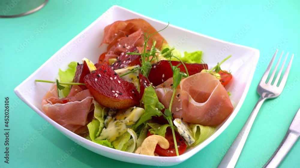 Pear salad, poached pear, dor blue cheese and prosciutto. Jamon meat with lettuce, cucumber. Healthy lunch with cashew nuts. Food in a white plate. Meat dish. Salad in a bowl. Sesame Pear salad, poached pear, dor blue cheese and prosciutto. Jamon meat with lettuce, cucumber. Healthy lunch with cashew nuts. Food in a white plate. Meat dish. Salad in a bowl. Sesame