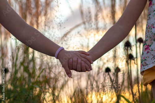 Hands of Two Girls Holding Each Other at Sunset