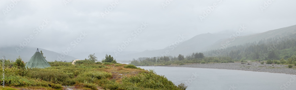 Rainy day on the Sob river in the Ural mountains. Tourist tents in anticipation of good weather. Mountains hidden by fog.