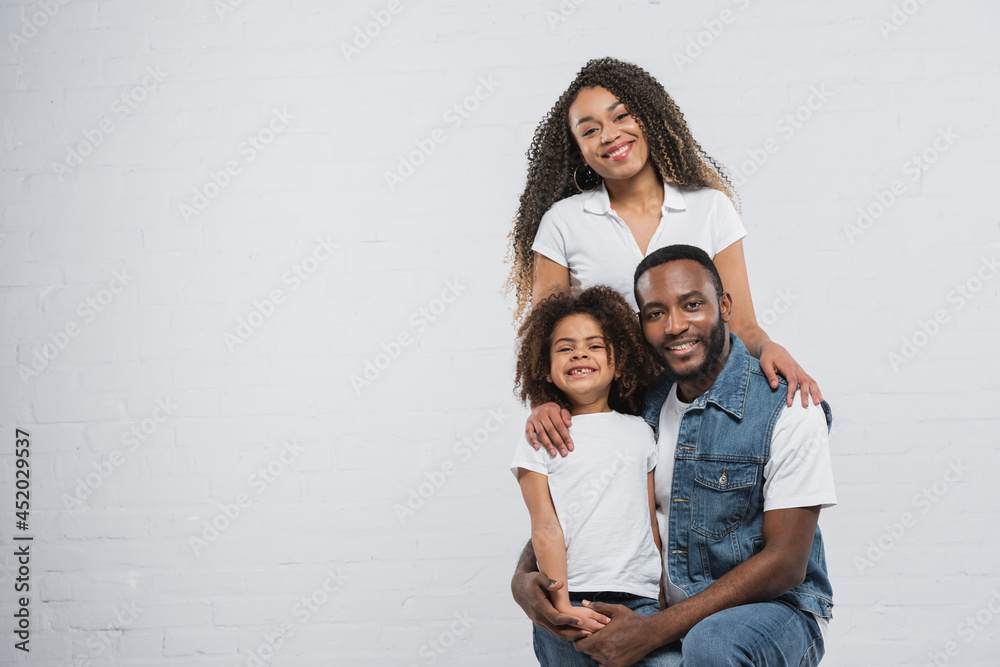 african american man hugging daughter near happy wife on grey african american man hugging daughter near happy wife on grey