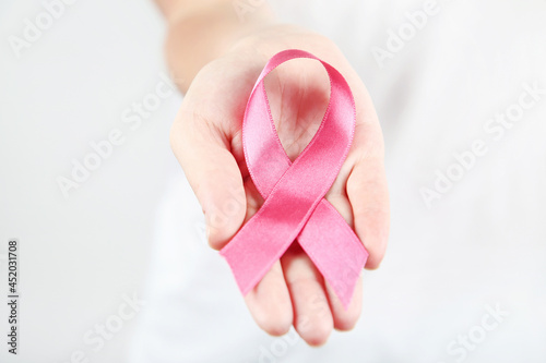 Breast cancer concept. Female hand with pink ribbon