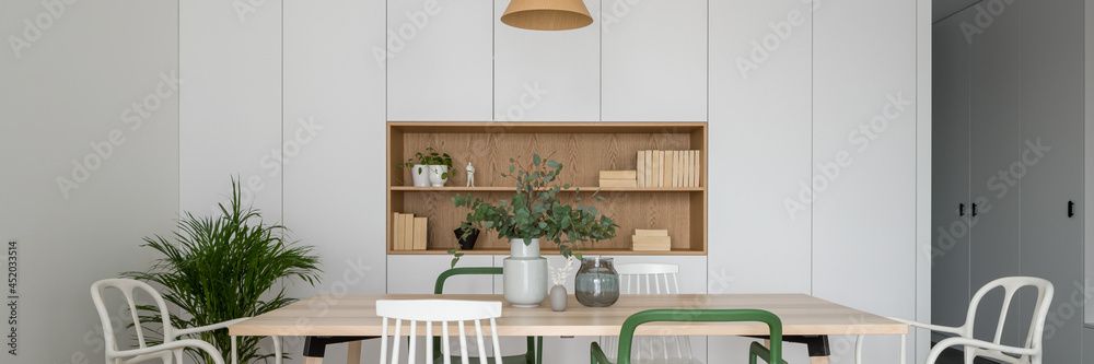 Stylish dining room with long table and different chairs, panorama