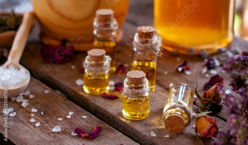 essential oil bottles with dry ingredients of St. John's wort, oregano and rose on the wood table with copy space	