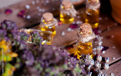 essential oil with dry oregano and lavender on the wooden table