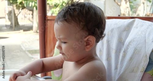 portrait of a child who eats baby food with his spoon. mother feeds the child on the outdoorat the children's table