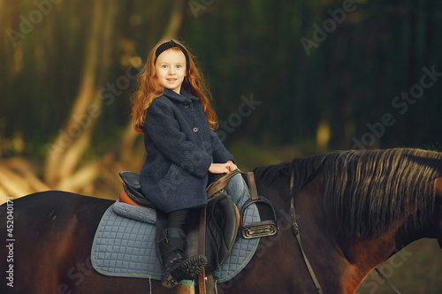 Cute little girl in a autumn field with horse