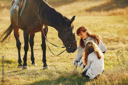 Vászonkép Mother and daughter in a field playing with a horse