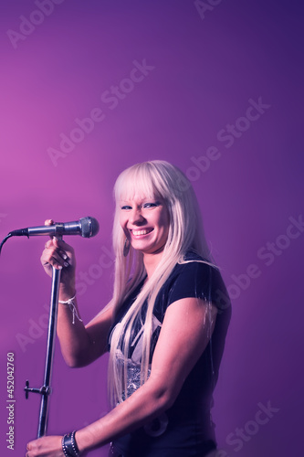 Close up photo beautiful funky blond lady on karaoke night hang out having fun playing rock star, casual black t-shirt over pink and violet background