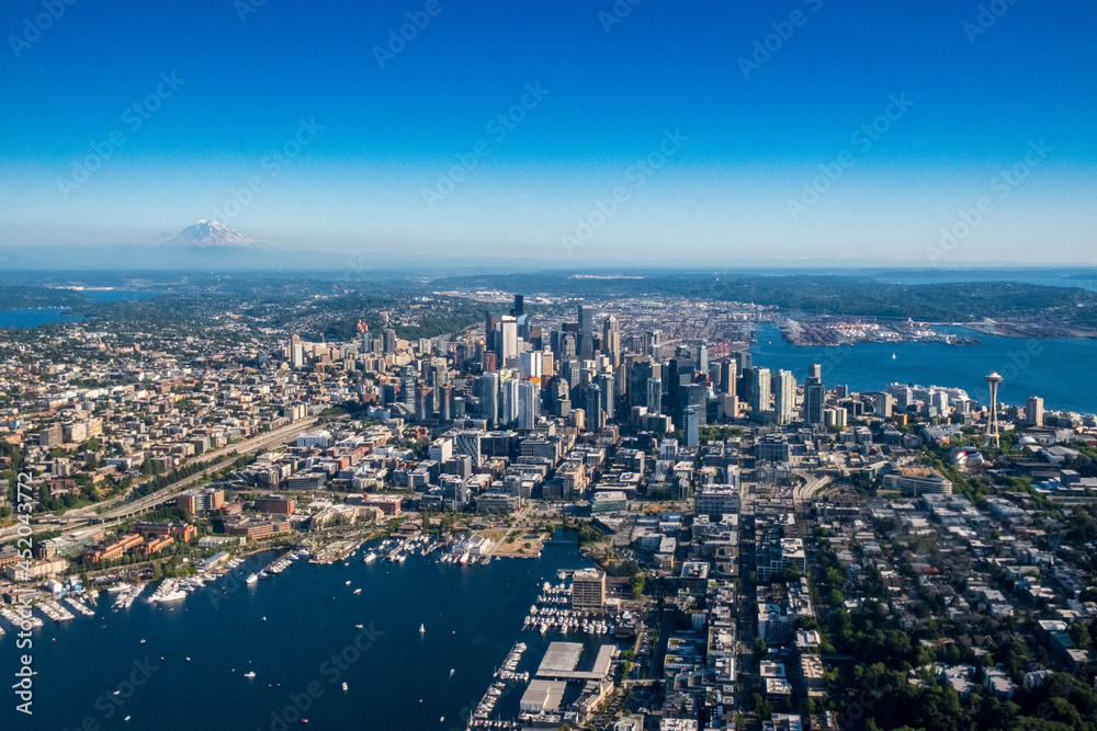 The Seattle skyline and surrounding areas as seen from the air on a clear blue sky day, with Mt. Rainier in the background The Seattle skyline and surrounding areas as seen from the air on a clear blue sky day, with Mt. Rainier in the background