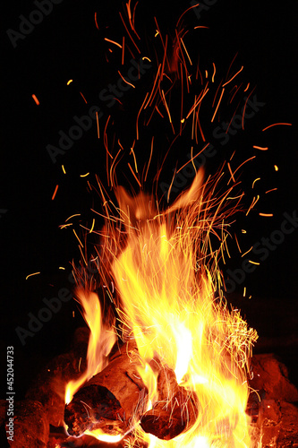 A burning fire, red sparks and yellow flames on a dark background