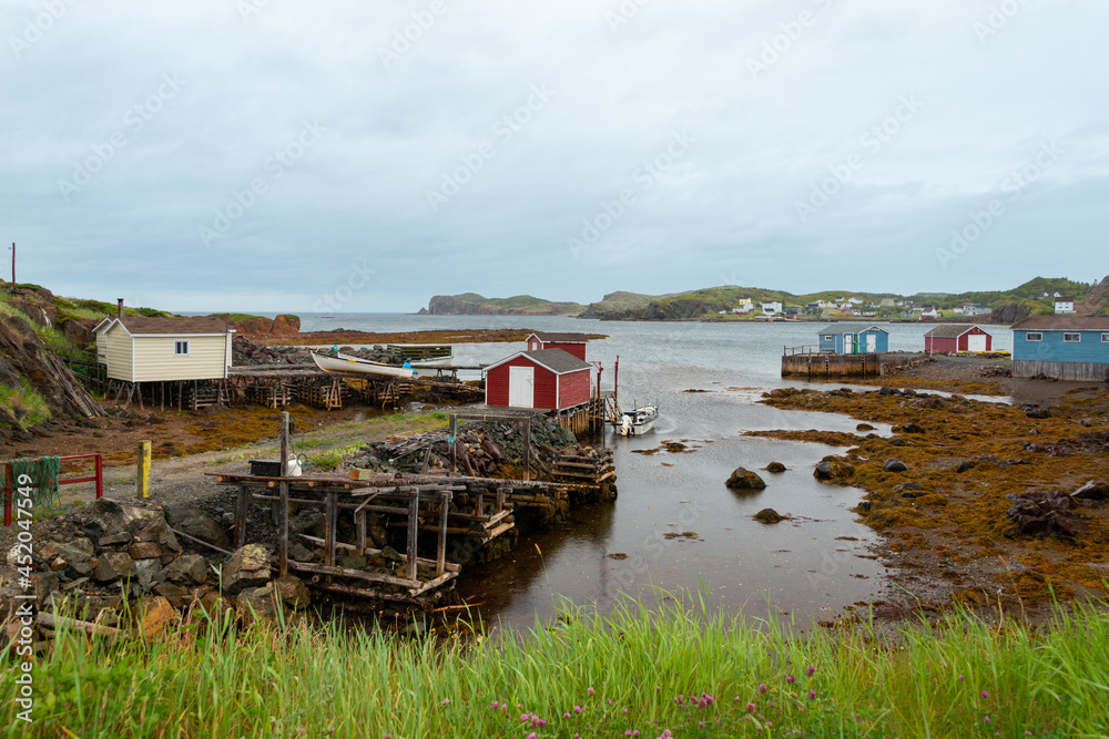 A view of Twillingate, Newfoundland, a small fishing village with a sheltered harbour surrounded by small fishing boats. The vintage houses surrounding the water are colorful wooden buildings. A view of Twillingate, Newfoundland, a small fishing village with a sheltered harbour surrounded by small fishing boats. The vintage houses surrounding the water are colorful wooden buildings.