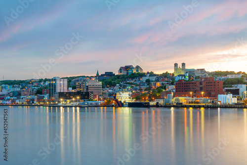 St. John's, Newfoundland, waterfront harbour at sunset. The lights on the water are bright yellow and orange which are reflecting from the skyline in the stillness of the smooth water.   photo
